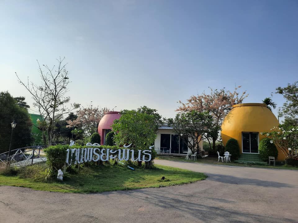 入口处的「บ้านพิริยะพันธ์」招牌，身后是粉色与黄色的水缸小屋